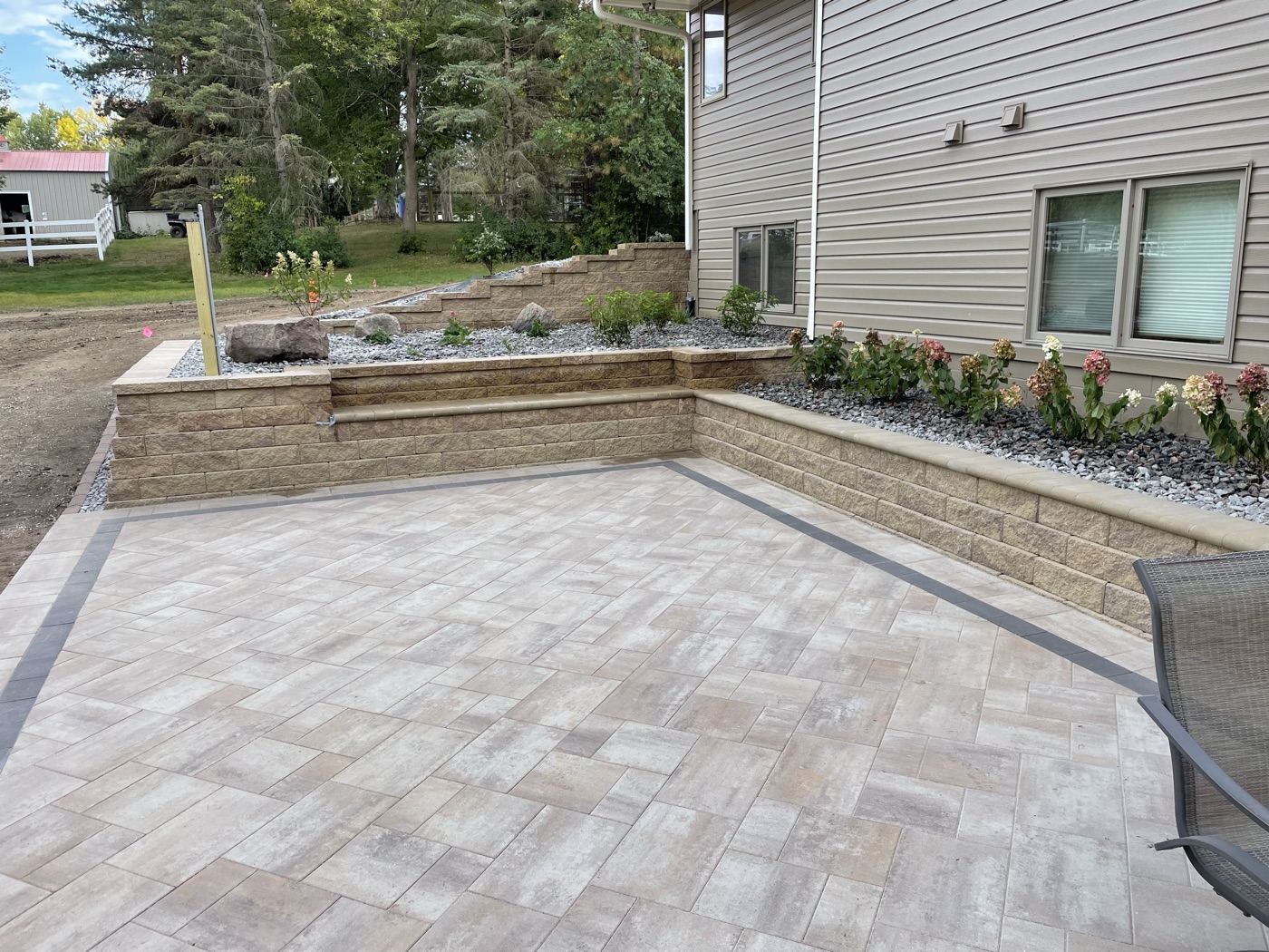 Paver patio with a natural stone seat wall and landscaped beds