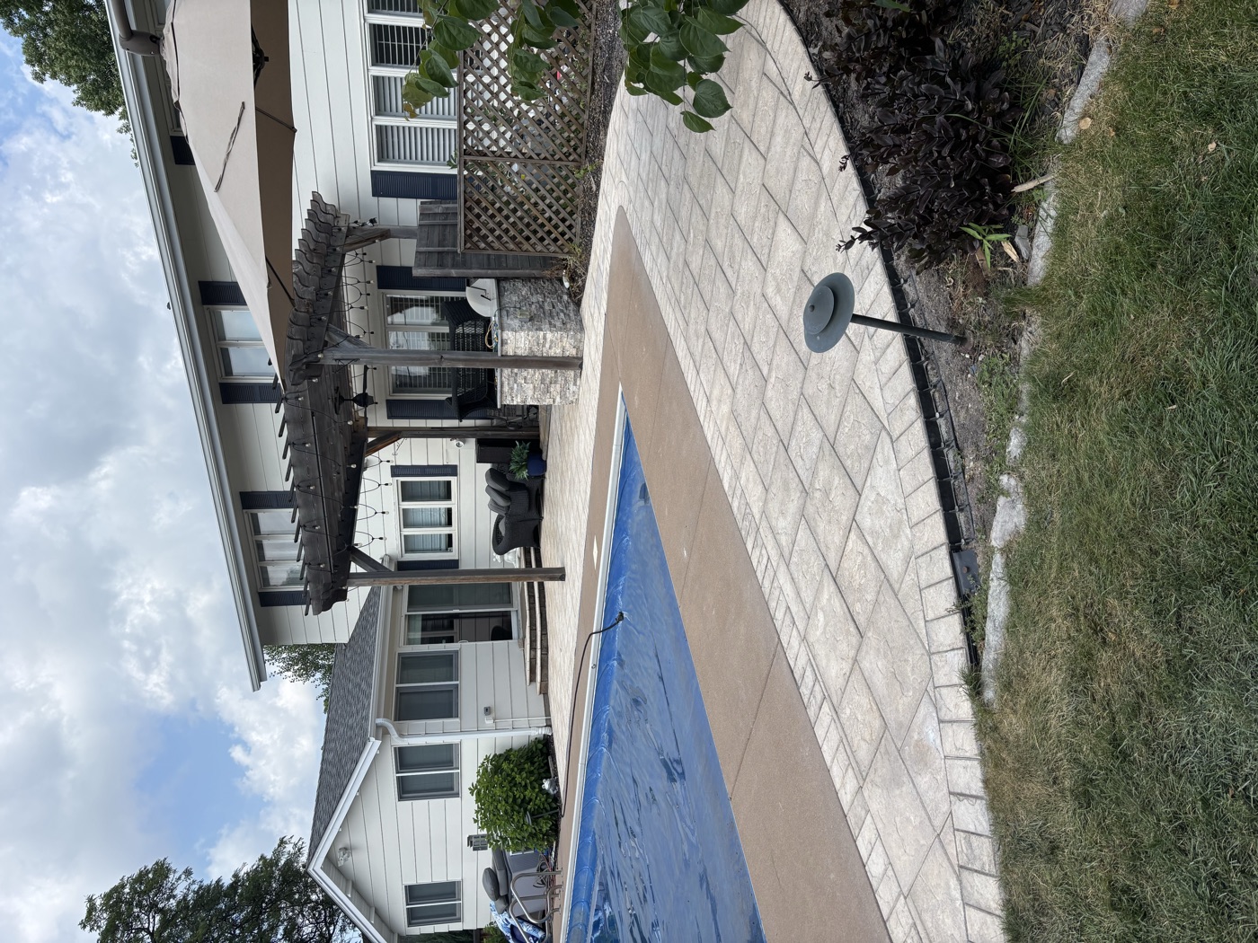 Paver pool deck with a pergola and outdoor living space