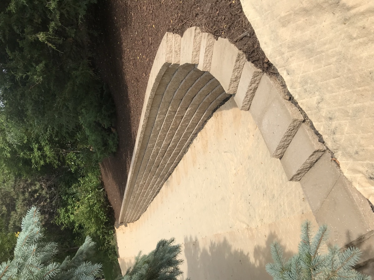 Curved tan block retaining wall with integrated steps