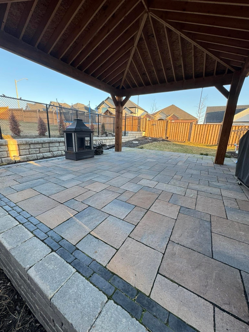 Covered paver patio with an outdoor fireplace and seat wall