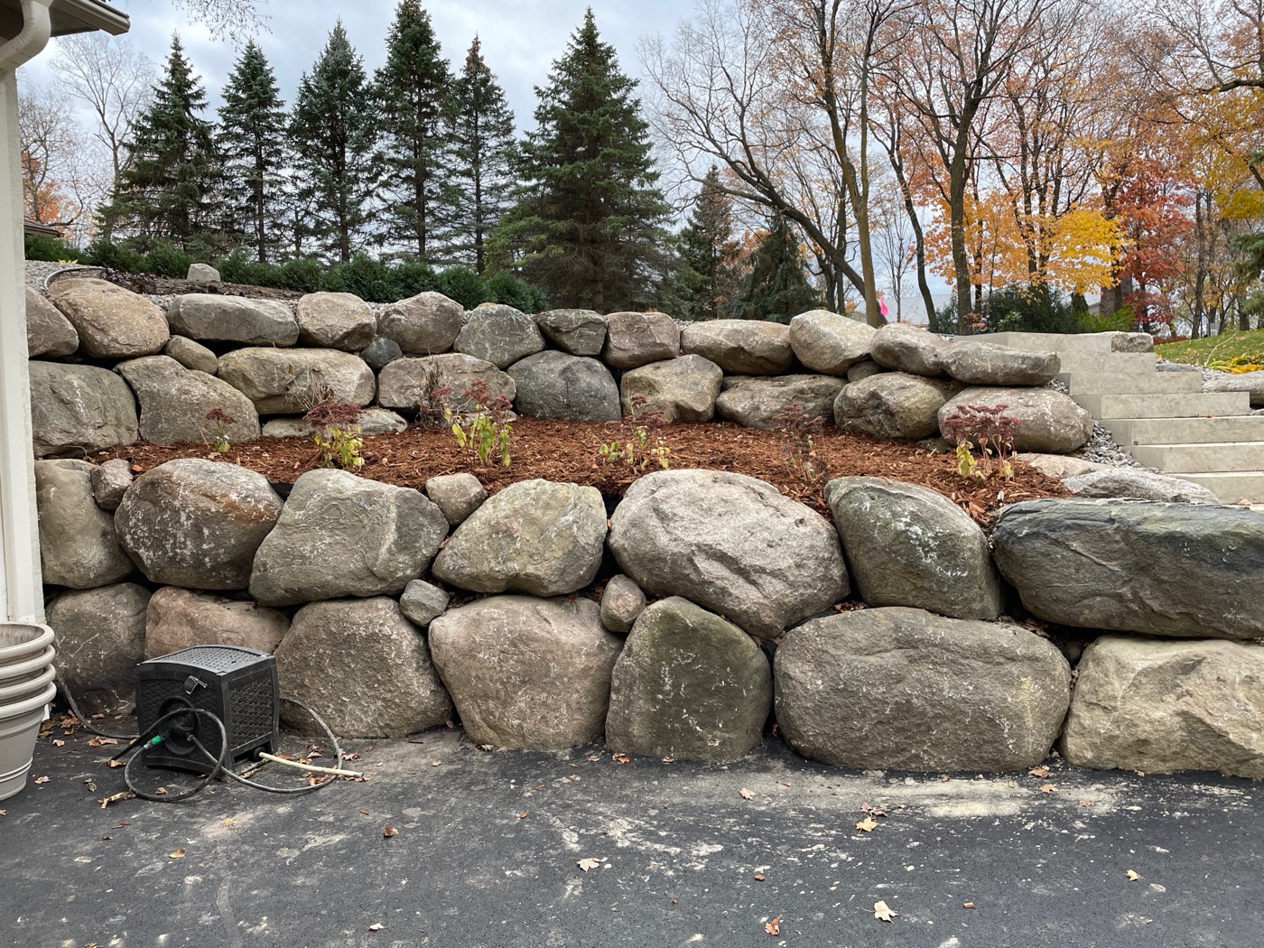 Terraced natural boulder retaining wall with mulched plantings